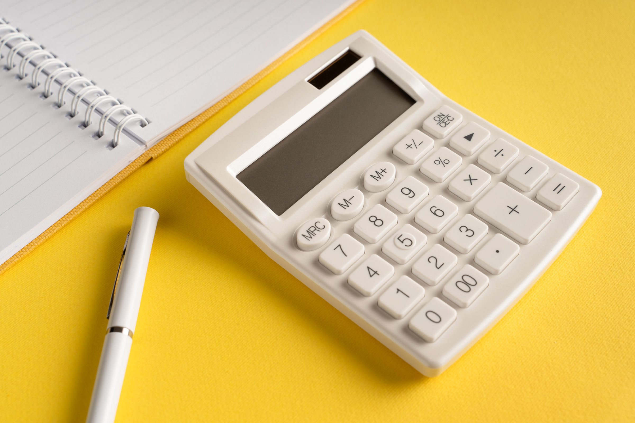 Office notebook with a pencil and a calculator on a yellow background